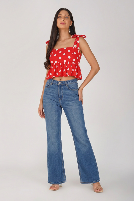 Woman wearing a red polka dot top and blue jeans on a white background