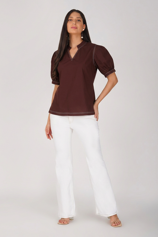 Woman wearing a brown top and white pants on a white background